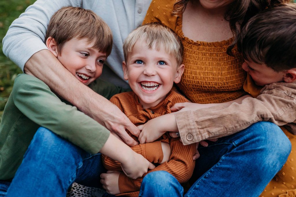 Family laughing and playing together during an outdoor family photo session in Newark, Ohio.