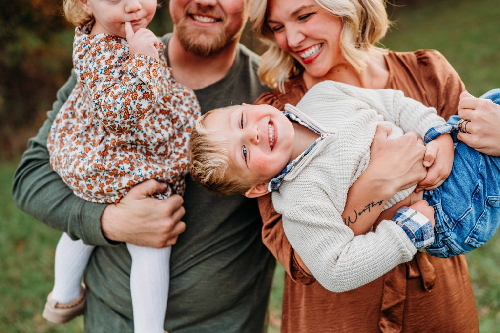 Parents laughing and playing with their two young children during a relaxed outdoor family photography session in Central Ohio.